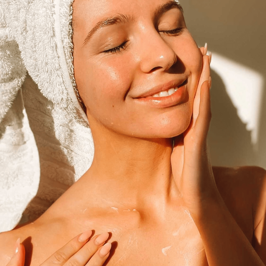 Person applying sunscreen on neck as part of a morning skincare routine