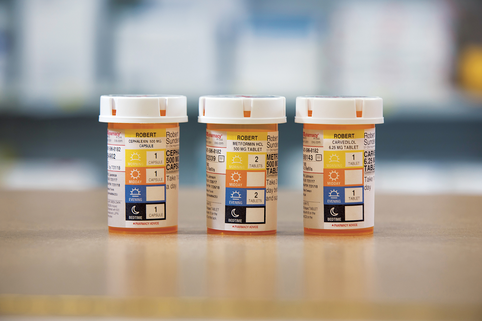 Prescription medication bottles clearly labeled with patient name, medication details, and dosage schedule icons for morning, midday, evening, and bedtime