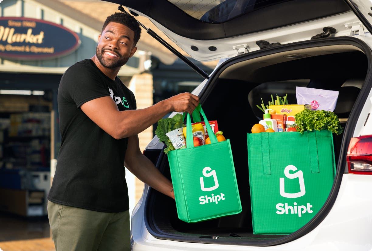 A Shipt shopper loading groceries into a car, illustrating the delivery service including potential prescription pickups