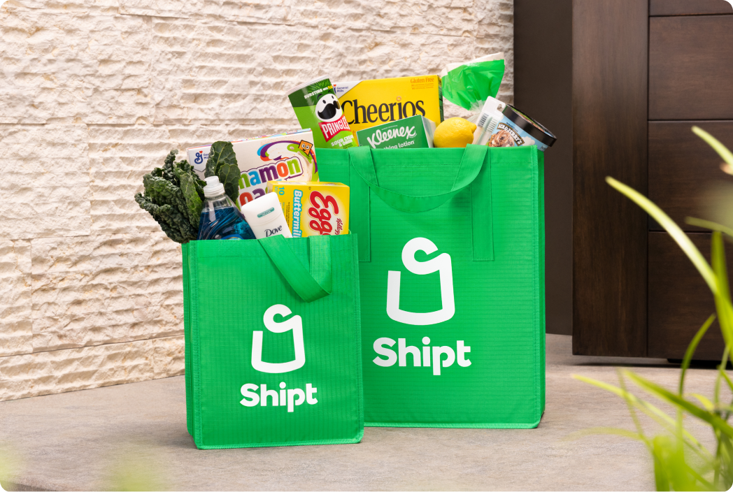 Shipt-branded green grocery bags filled with assorted groceries illustrating Shipt's home delivery service