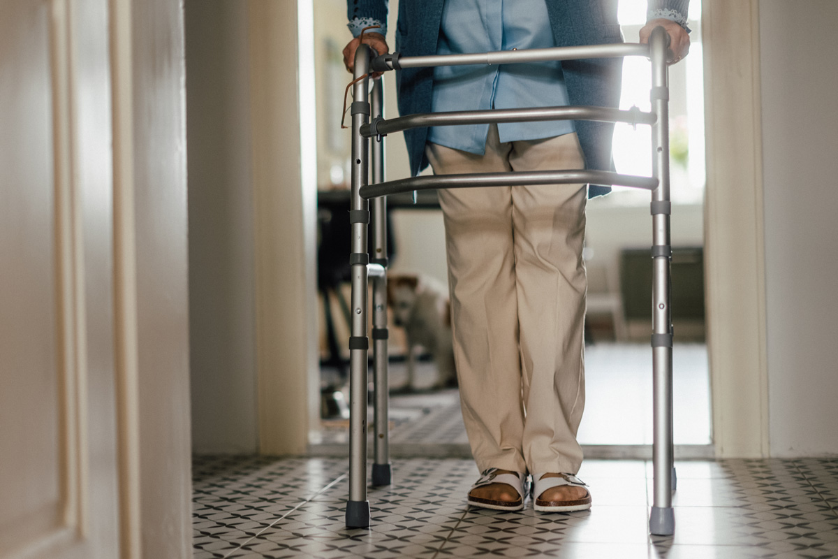 An elderly person using a walker indoors to aid mobility