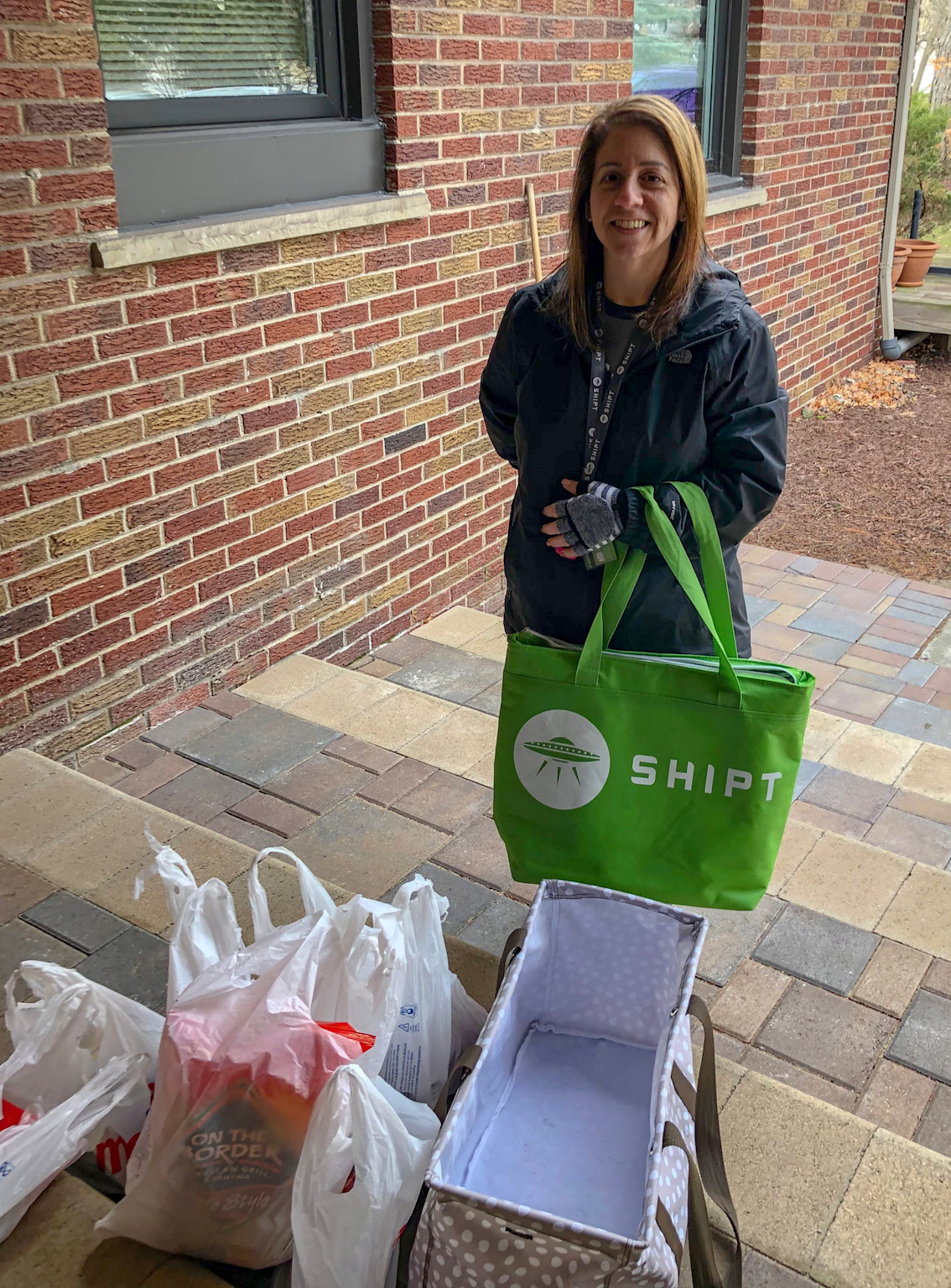 Shipt delivery shopper holding a branded bag with grocery items, illustrating Shipt's service that may include prescription pick-ups